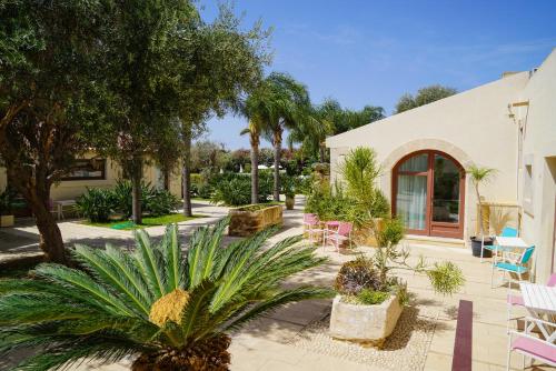 einen Innenhof mit Palmen und Stühlen sowie ein Gebäude in der Unterkunft Life Hotels Kalaonda Resort in Syrakus