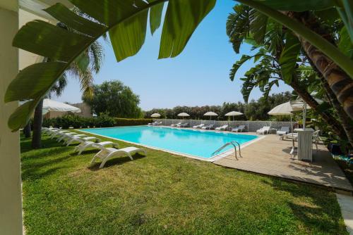 a swimming pool with lounge chairs and umbrellas at Life Hotels Kalaonda Resort in Siracusa