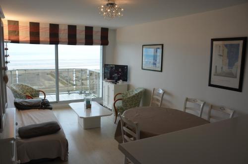 un salon avec une table et des chaises et une fenêtre dans l'établissement Superbe appartement en résidence avec parking, à Le Touquet-Paris-Plage