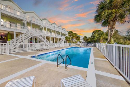 a swimming pool with two chairs next to a building at Beach Blessings Luxe 30A Townhome 2BR 3Bath, Walk to Beach, Pool, Hot Tub in Santa Rosa Beach
