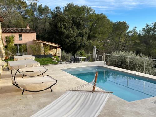 a pool with a hammock next to a house at Villa Horizon - Piscine privée in Montauroux