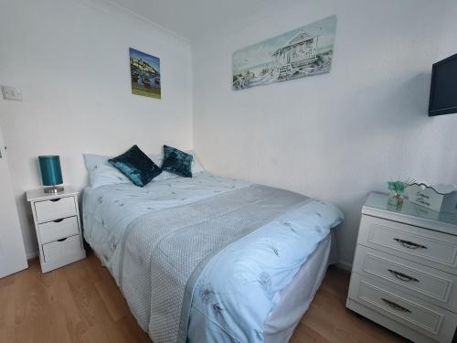 a white bedroom with a bed and a night stand at Isle of Wight Chalet in Sandown