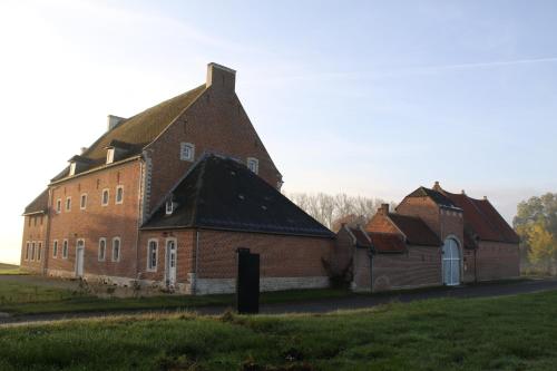 a large brick building with a gambrel roof at Hoeve Luitenant Halleux in Linter