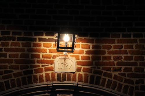 a light on a brick wall with a sign on it at Hoeve Luitenant Halleux in Linter