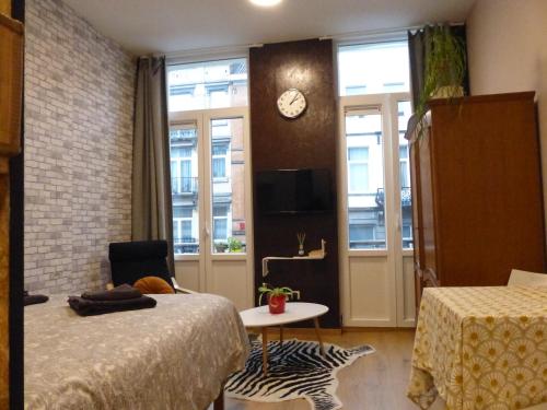 - une chambre avec un lit et une horloge murale dans l'établissement Superbe Studio au 1er étage, proche de la gare du Midi, à Bruxelles