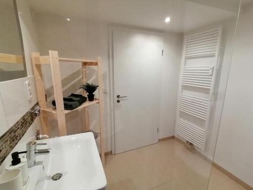 a bathroom with a white sink and a door at Filder-Apartment in Filderstadt