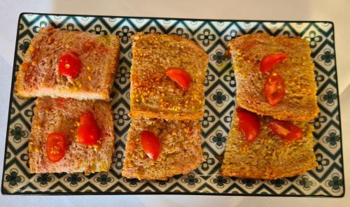 a plate with three slices of bread with tomatoes on it at Hotel Perla Del Mare in Lido di Camaiore