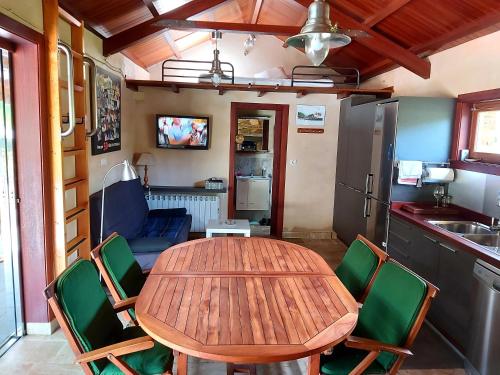 a kitchen with a wooden table and green chairs at Casetón do Forno. in Lourenzá