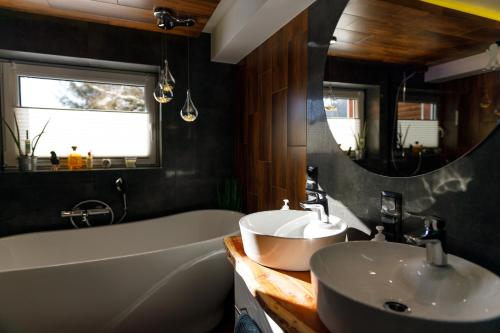 a bathroom with a sink and a tub and a mirror at APARTAMENT POD ŚLIWKAMI in Krynica Zdrój
