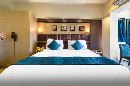 a bedroom with a large bed with blue pillows at Hotel Oriental Aster - Mumbai International Airport in Mumbai