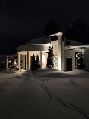 a white house in the snow at night at Pikkukoti Villa in Keuruu