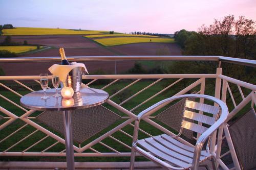 a table and a chair on a balcony with wine glasses at Zur Morschbach in Altlay