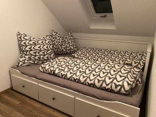 a bed with black and white pillows on it at Ferienwohnung Auersbergblick in Schönheide
