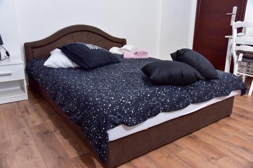 a bed with black pillows on it in a room at Apartmani Koko in Banja Luka