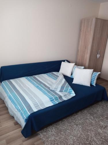 ein blaues Bett mit zwei Kissen in einem Zimmer in der Unterkunft Apartman Nera in Zenica