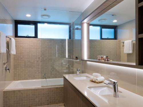 a bathroom with a sink and a tub and a mirror at Glen Hotel and Suites in Brisbane