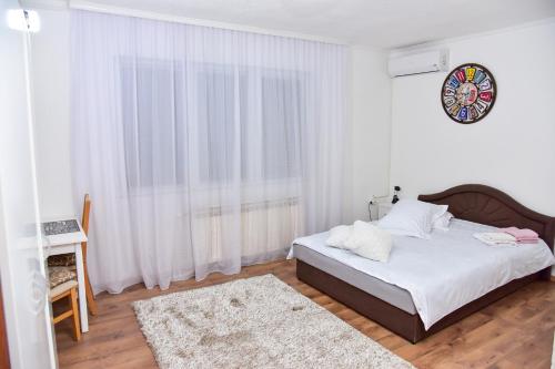 a white bedroom with a bed and a window at Apartmani Koko in Banja Luka