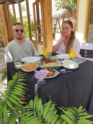 a man and a woman sitting at a table with food at Manta Dhangethi in Dhangethi