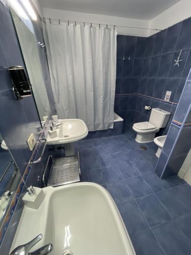 een blauwe badkamer met een bad, een wastafel en een toilet bij RentOnTheBeach in Los Cristianos