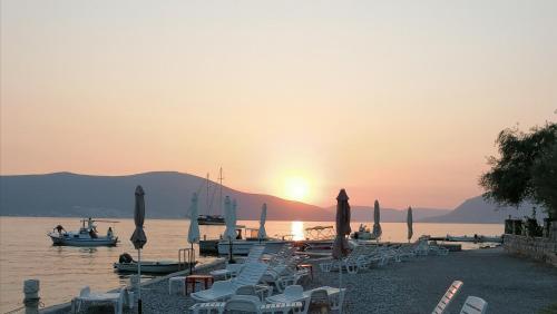 a group of chairs and umbrellas on a beach with the sunset at Olea in Tivat