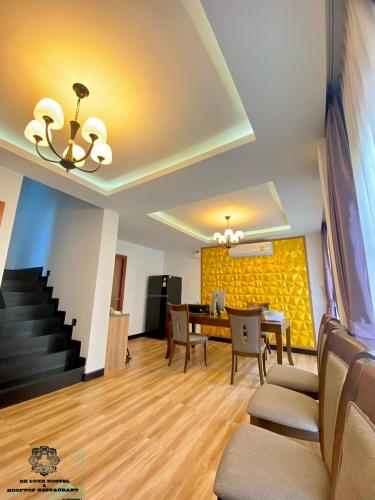 a dining room with a table and a yellow wall at DE LUXE BOUTIQUE & rooftop in Chiang Mai