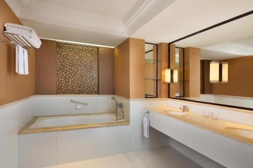 y baño con 2 lavabos, bañera y espejo. en Sheraton Mustika Yogyakarta Resort and Spa, en Yogyakarta