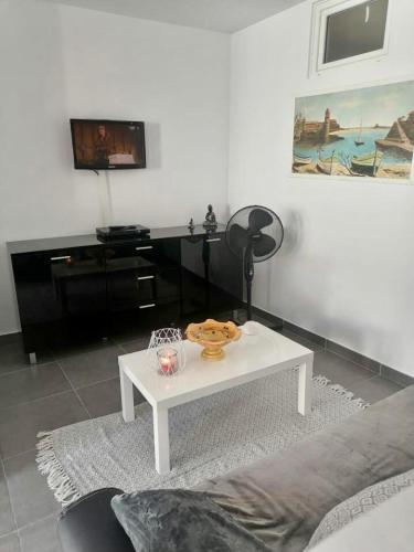 a living room with a white table and a tv at Appartement entièrement rénové in Cerbère