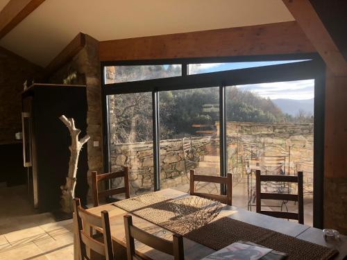 a dining room with a table and a large window at La Bergerie in Saint-Vincent