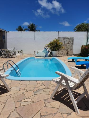 a large swimming pool with two chairs and a table at Casa de Praia - Francês/Marechal Deodoro in Marechal Deodoro