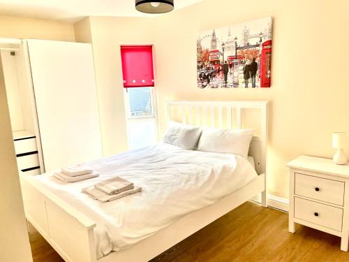 a bedroom with a white bed with two towels on it at Holiday Flat in Central Slough near to London Heathrow and Windsor with Free Car Park in Slough