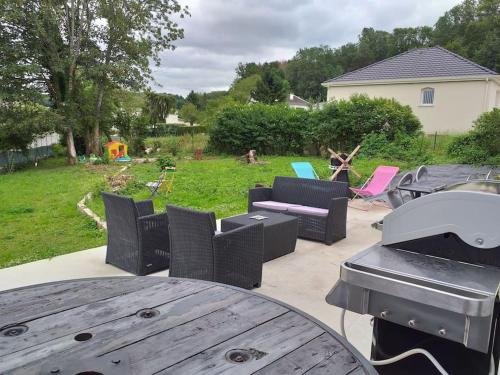 een patio met een tafel en stoelen en een grill bij maison à la campagne prés de la ville in Aiglemont