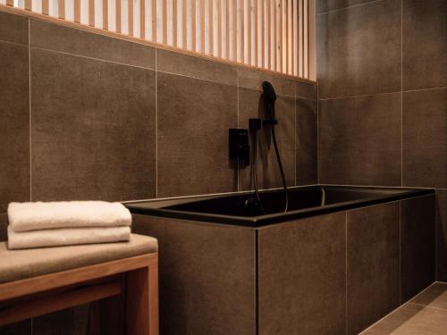 a bathroom with a black tub and a sink at JOHANN Schladming in Schladming