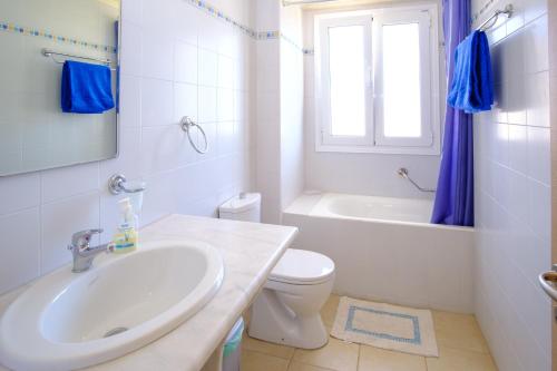 a bathroom with a sink and a toilet and a window at Villa Poppy in Vathi