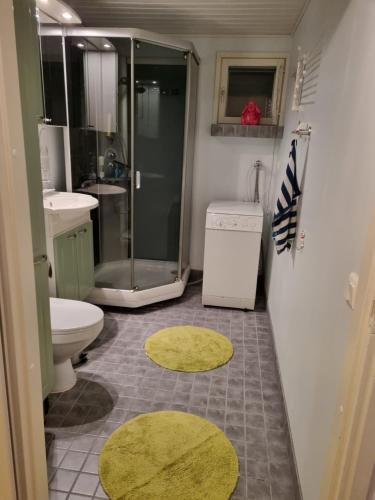 W łazience znajduje się prysznic, toaleta i żółte dywany. w obiekcie Apartment Oulu Varjakka w mieście Oulunsalo