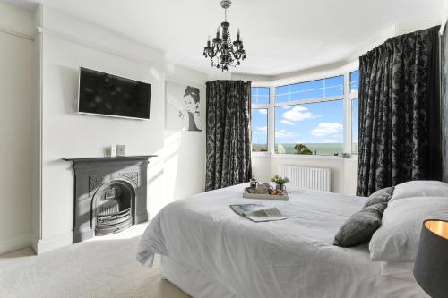 a white bedroom with a fireplace and a bed at Family Home By The Sea in Torquay