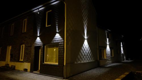a building with lights on the side of it at night at La Tanière des Loups in Herbeumont