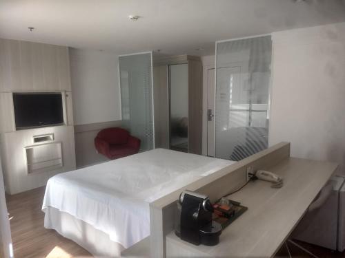 a bedroom with a large white bed and a television at Flat Brasília Líder - Eixo Monumental in Brasília