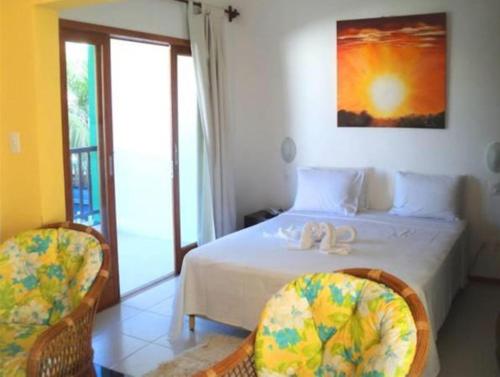 a bedroom with a white bed with two chairs at Tree Bies Resort, Simplesmente Maravilhoso! in Entre Rios