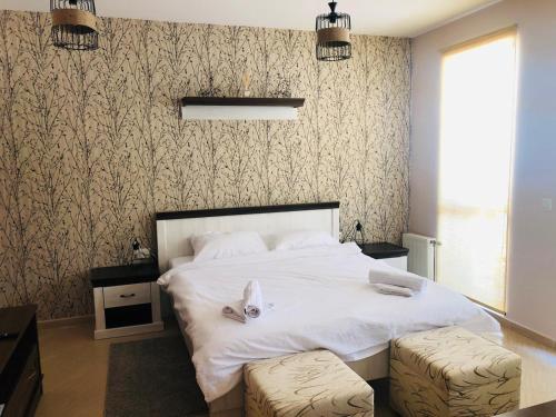 een slaapkamer met een groot wit bed met 2 krukken bij Mouse&Mutton Studios in Green Life Ski&Spa Bansko in Bansko