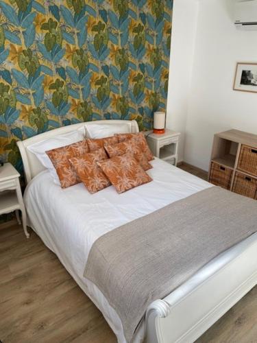 une chambre avec un lit blanc avec des oreillers orange dans l'établissement Villa Madhi - Piscine privée, à LʼIsle-sur-la-Sorgue
