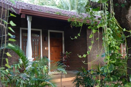 ein Backsteinhaus mit einer Eingangstür und Pflanzen in der Unterkunft So-J Beach Villa in Trincomalee