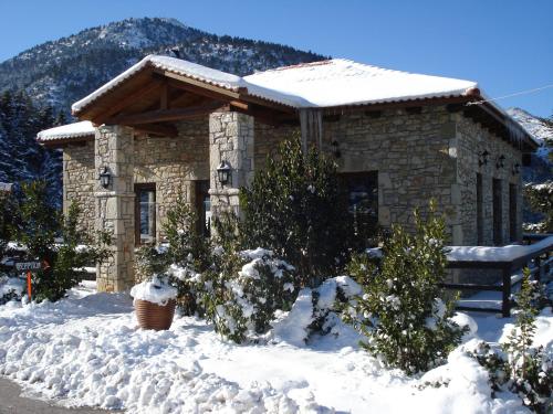 a stone house with snow in front of it at Georgio's V Chalet Kalavrita in Kalavrita