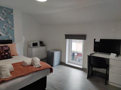 a bedroom with a bed and a desk with a computer at Double Ensuite Rooms in Swansea