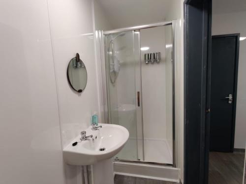 a white bathroom with a sink and a shower at Double Ensuite Rooms in Swansea