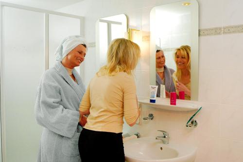 a woman standing in a bathroom looking at herself in the mirror at Hotel-Pension Bergkranz in Braunlage