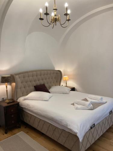 a bedroom with a large bed and a chandelier at Historical Center Residence 1 in Sibiu