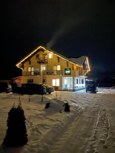 a large house in the snow at night at Pensiunea Andres in Sovata
