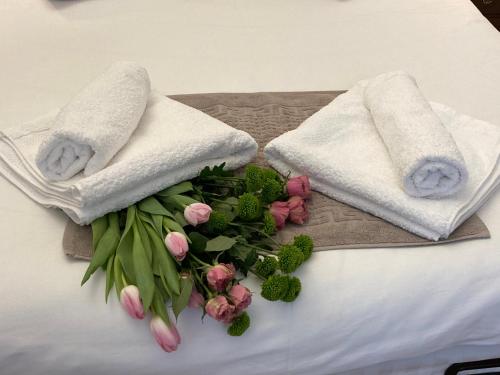 a bunch of pink flowers and towels on a bed at Historical Center Residence 1 in Sibiu