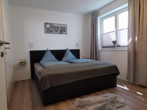 ein Schlafzimmer mit einem Bett mit blauen Kissen und einem Fenster in der Unterkunft Appartement Lifestyle in Ehrwald