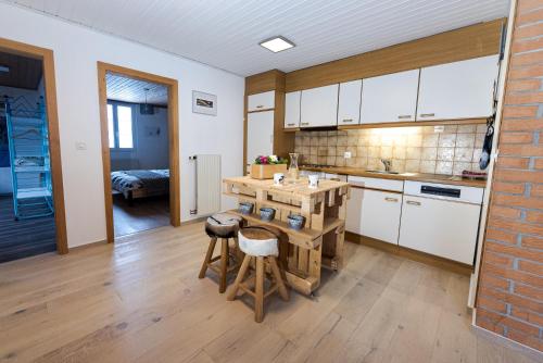 a kitchen with white cabinets and a wooden table at Vent_du_Nord in Tramelan